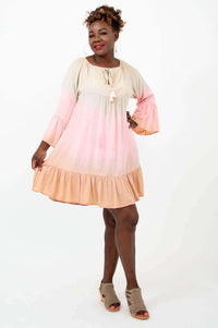 Woman wearing a ruffled hem ombre dress, posing with arm extended