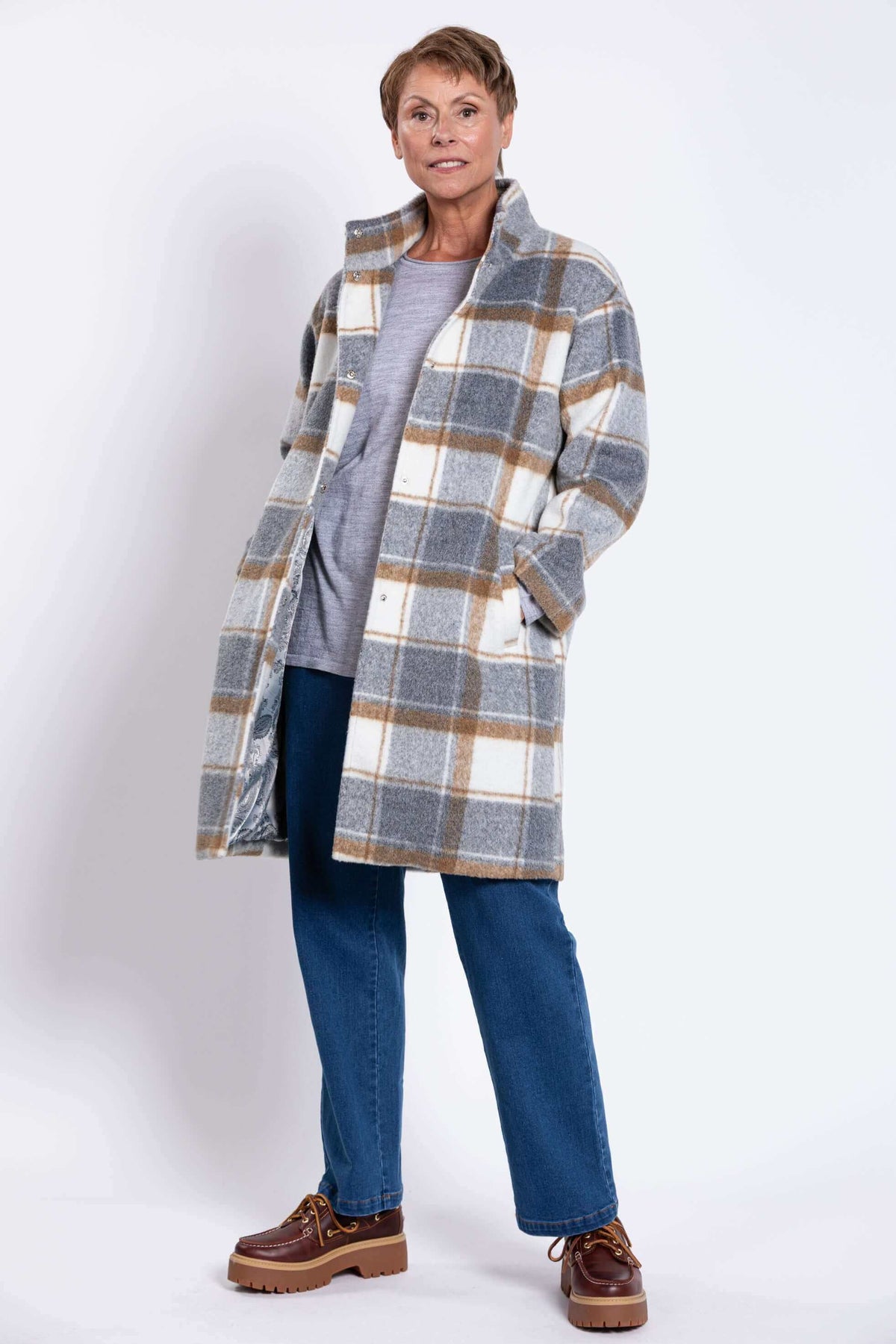 Woman standing with open plaid wool coat, showing lined interior