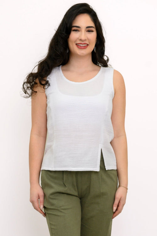 Woman wearing a white sleeveless top and green pleated pants on a white background, front view
