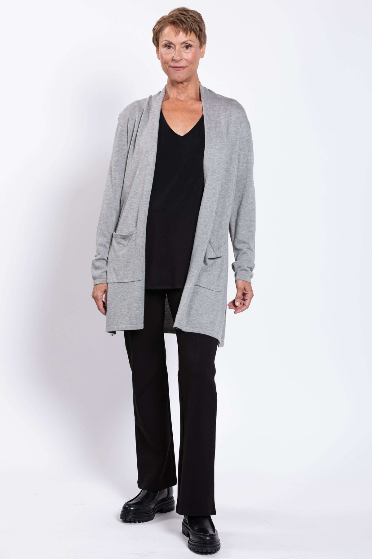 Woman modeling a grey cardigan with patch pockets and relaxed fit over black clothing