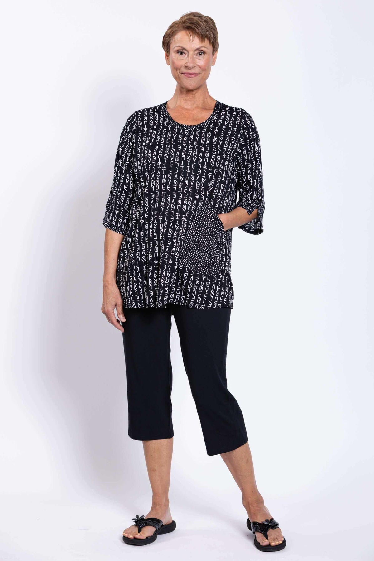 Woman posing with hand in front pocket of Palace Blouse, black abstract print