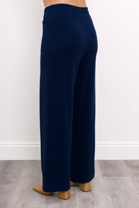 Rear angled view of woman wearing high-waisted navy blue pants with elastic waistband