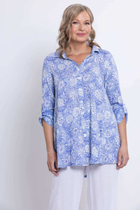 Woman in blue paisley bamboo linen shirt, partial front view with white pants