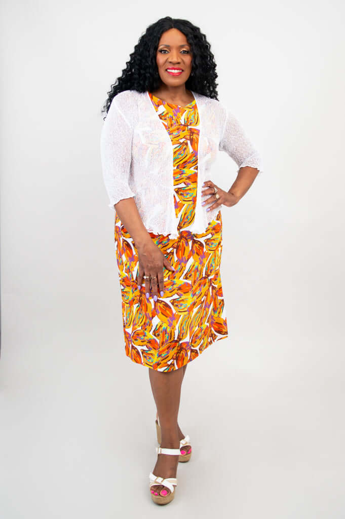 Woman wearing a colorful shift dress paired with a white open-front shrug