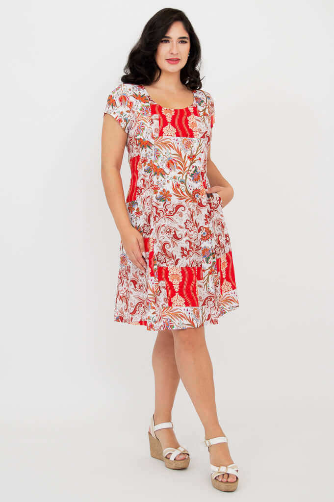 Woman posing in a patterned red and white dress with hands in pockets