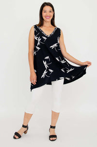 Woman showcasing the flowy hem of a black sleeveless tunic with white floral print