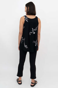 Back view of woman in a black flowy tank top with white shell and starfish pattern