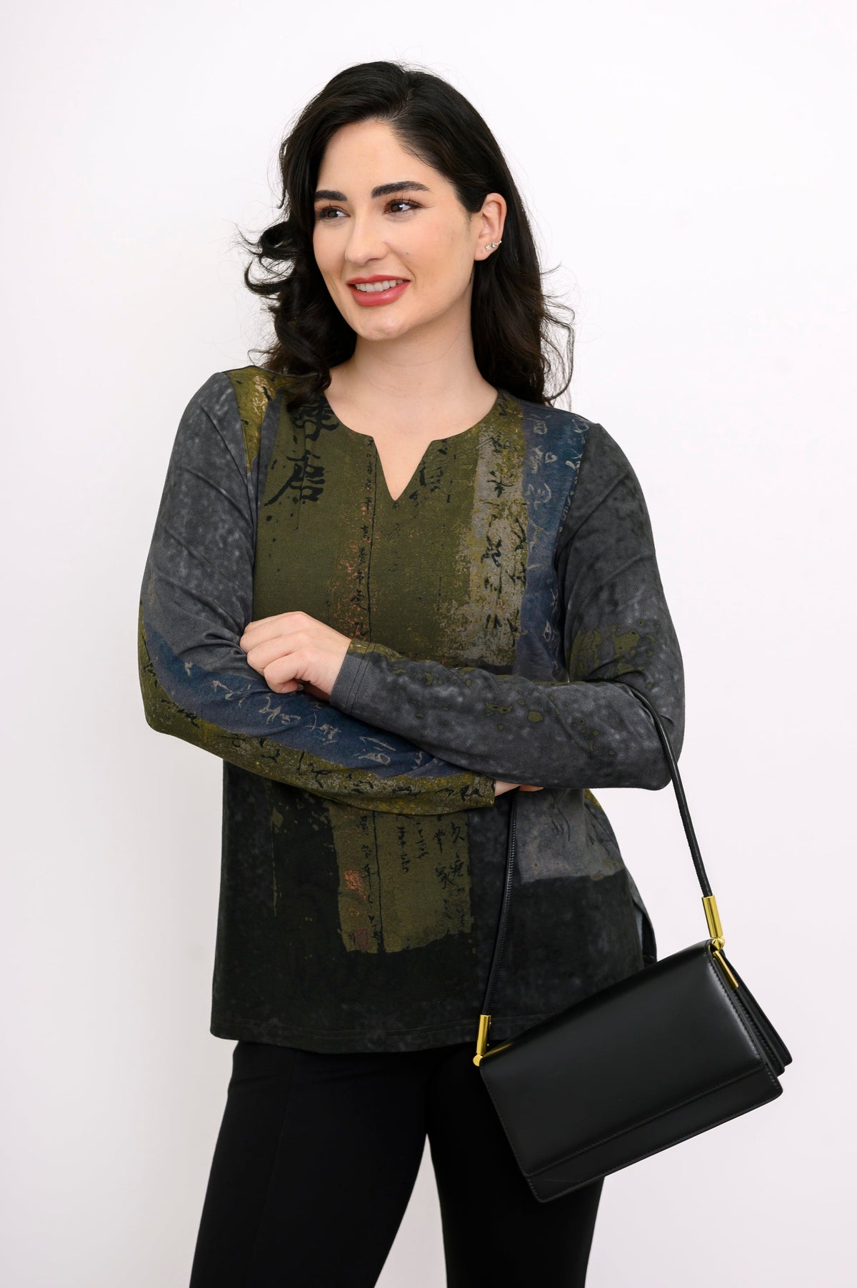 Model in a patterned green long-sleeve bamboo shirt and black pants, carrying a black shoulder bag.