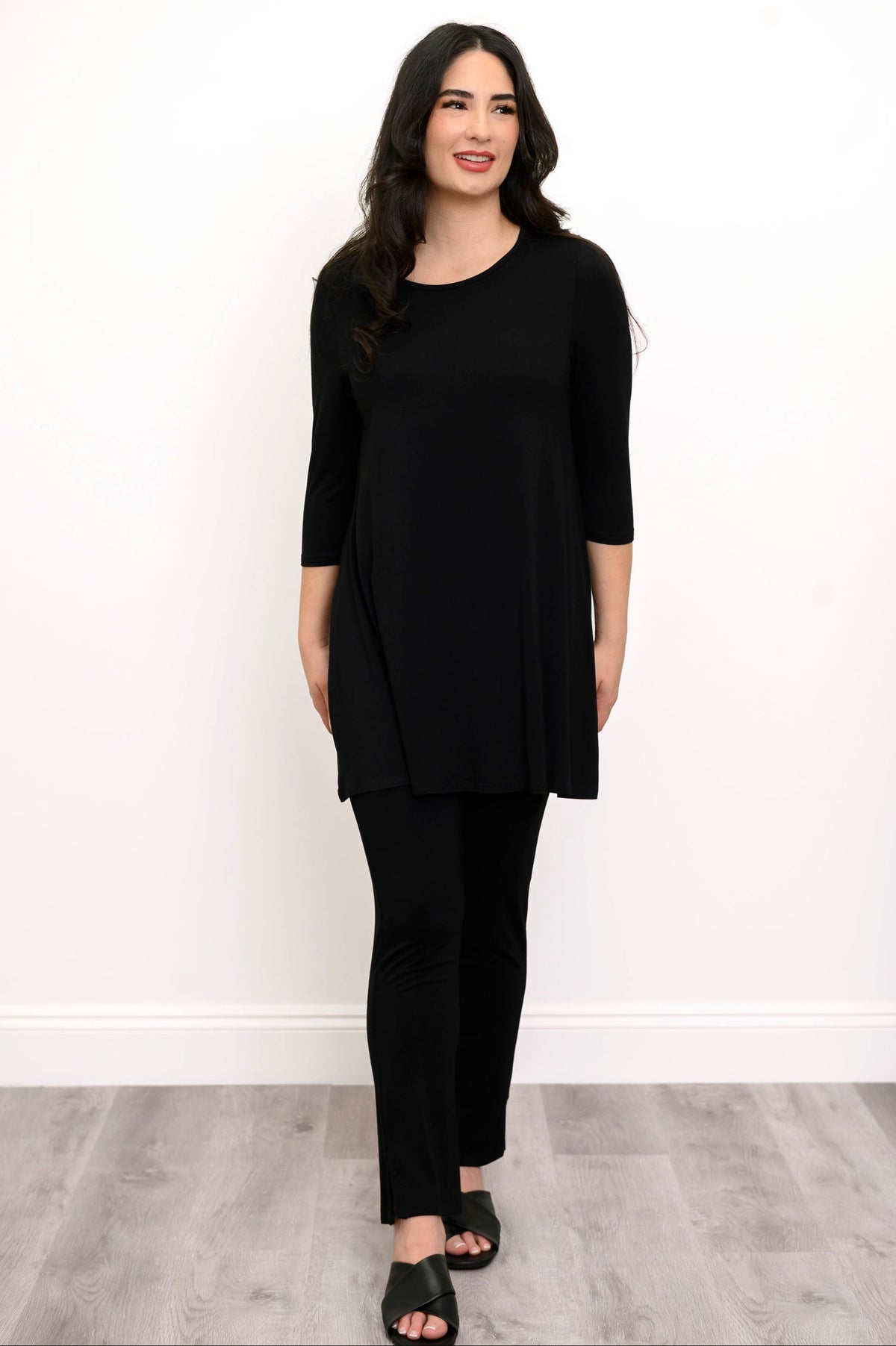 Woman wearing a black tunic, black pants, and back sandals