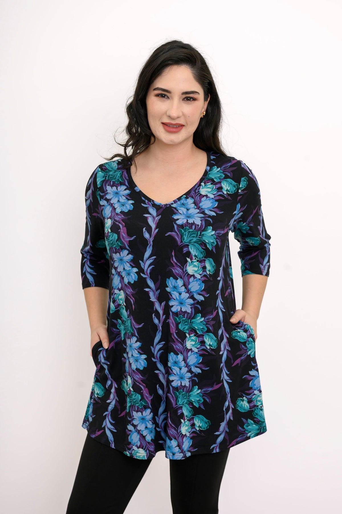Model posing in a flowy blue-teal floral print bamboo tunic showing the flattering hip-covering length.