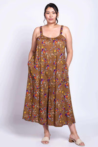 Person wearing a brown floral jumpsuit with hands in pockets, facing forward