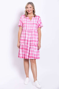 Front view of woman smiling in pink checkered dress with white sneakers