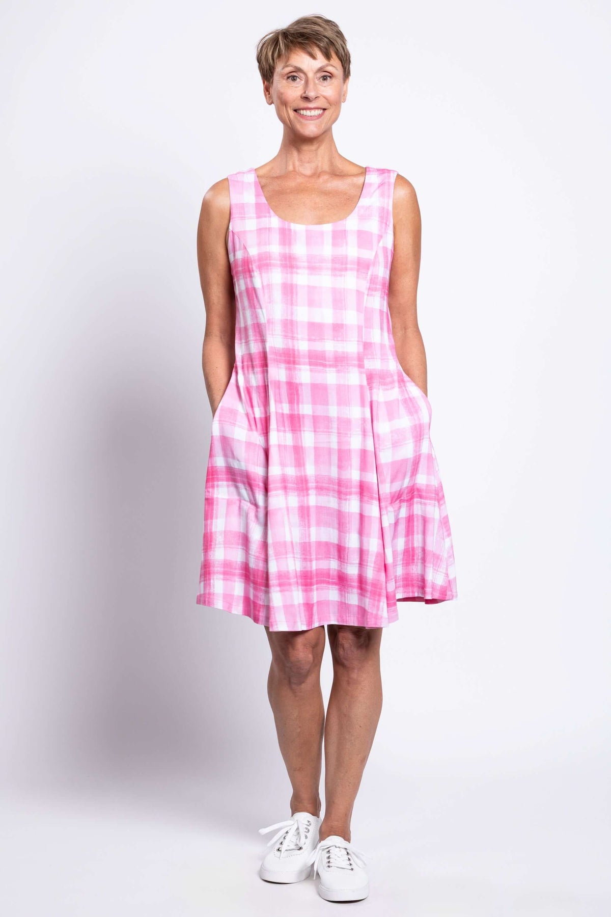Woman with hands in pockets wearing a pink plaid sleeveless A-line dress