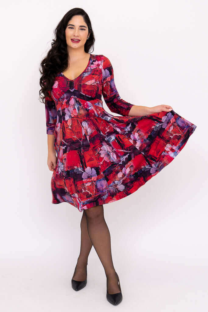 Woman holding out skirt, showing the playful movement of a red floral V-neck dress with 3/4 sleeves