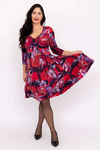 Woman holding out skirt, showing the playful movement of a red floral V-neck dress with 3/4 sleeves
