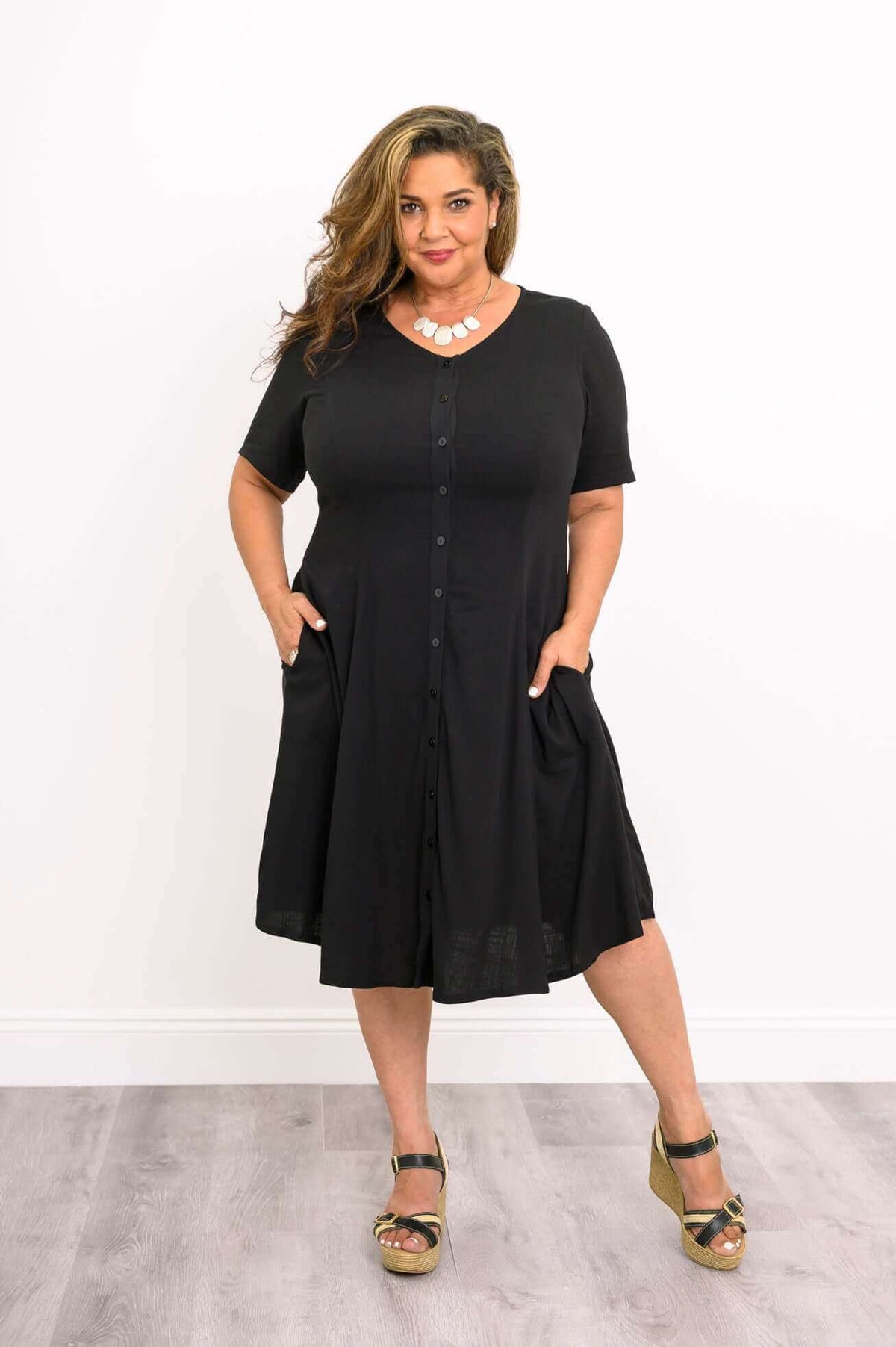 Plus-size woman posing in a black button-front dress with pockets
