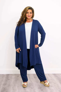 Plus-size model wearing navy open front duster, white top, matching pants, and wedge sandals