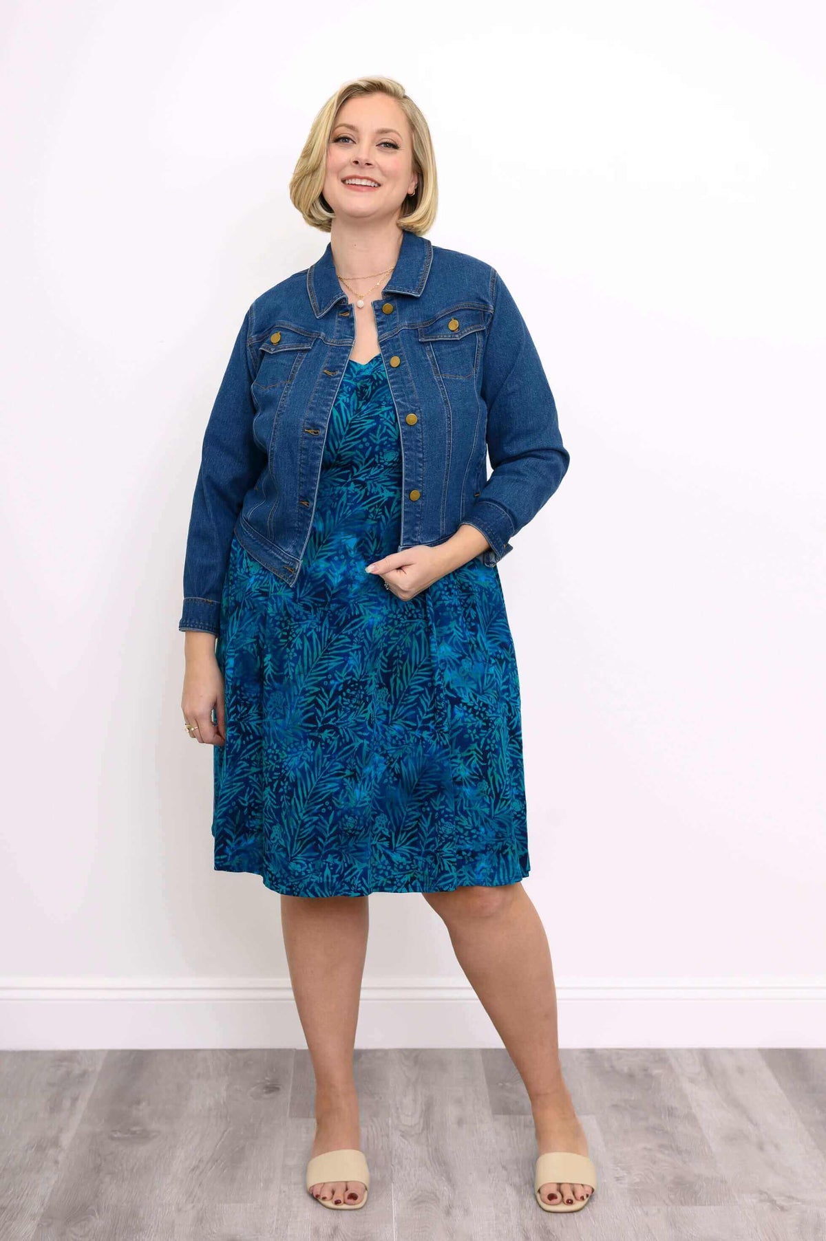Plus size model in a blue tropical A-line dress paired with a denim jacket