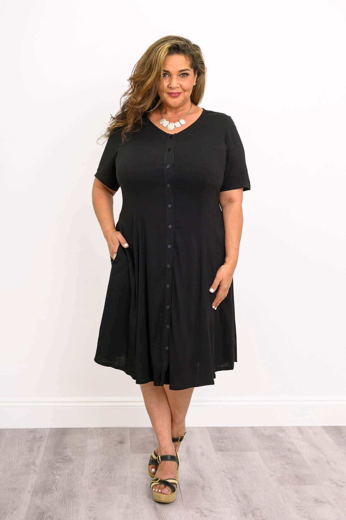 Plus size model in black button-up dress with pockets and statement necklace