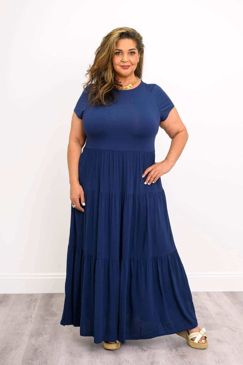 Plus size model wearing navy blue tiered maxi dress with short sleeves