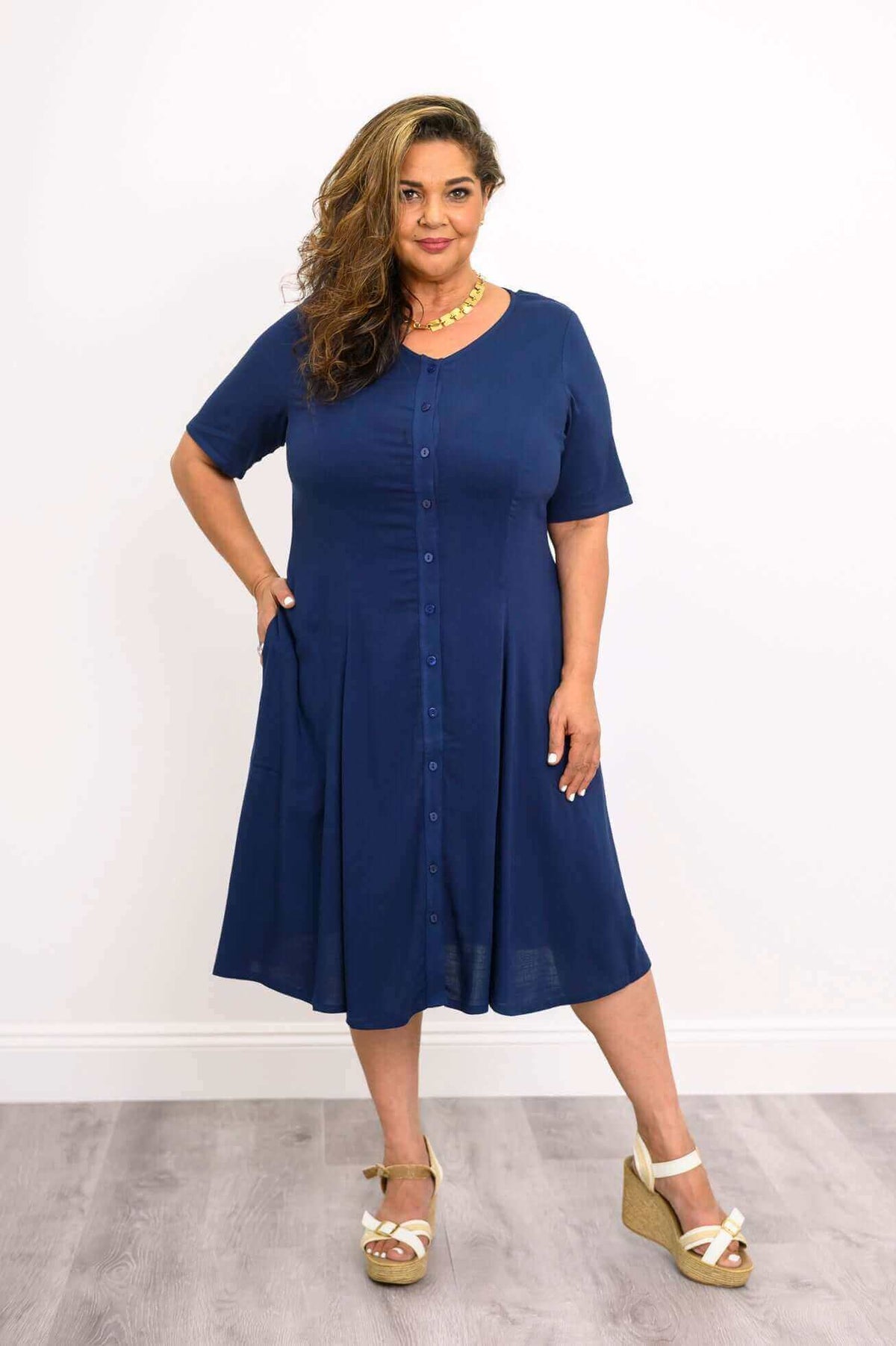 Plus size model in navy button-front dress with pockets and wedge sandals