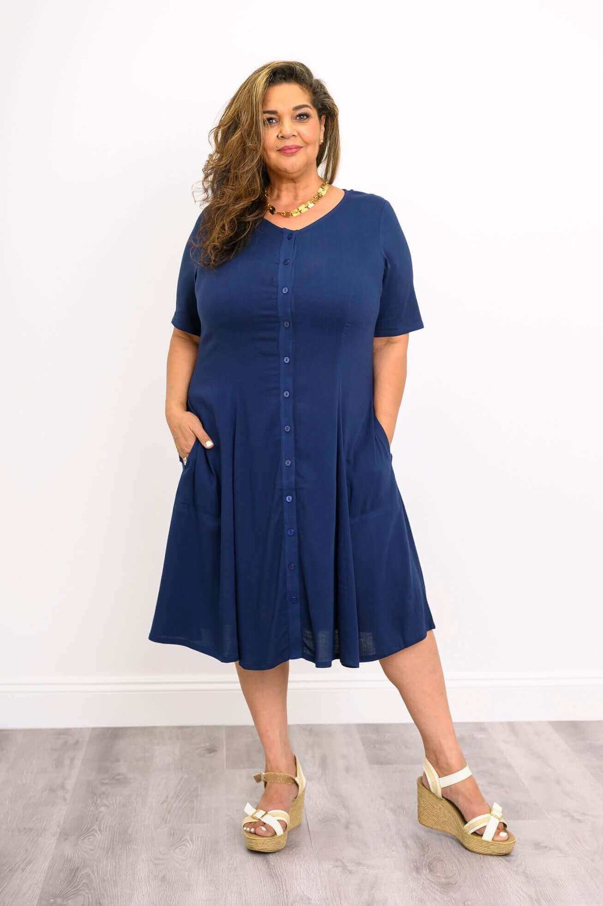 Plus size model showcasing navy dress with short sleeves and hands in pockets