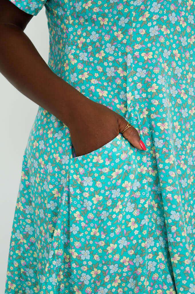 Close-up of hand in pocket on teal and pastel floral print dress