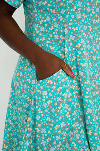 Close-up of hand in pocket on teal and pastel floral print dress