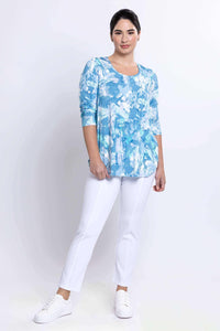 Model posing in blue watercolor Jazz Top with white pants and sneakers
