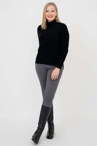 Woman posing in black mock neck sweater and grey pants with black boots