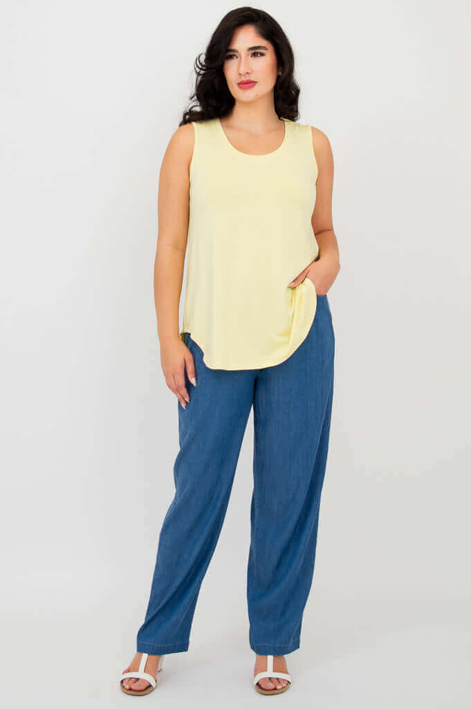 Model posing with hand in pocket, wearing lemon bamboo tank and blue pants