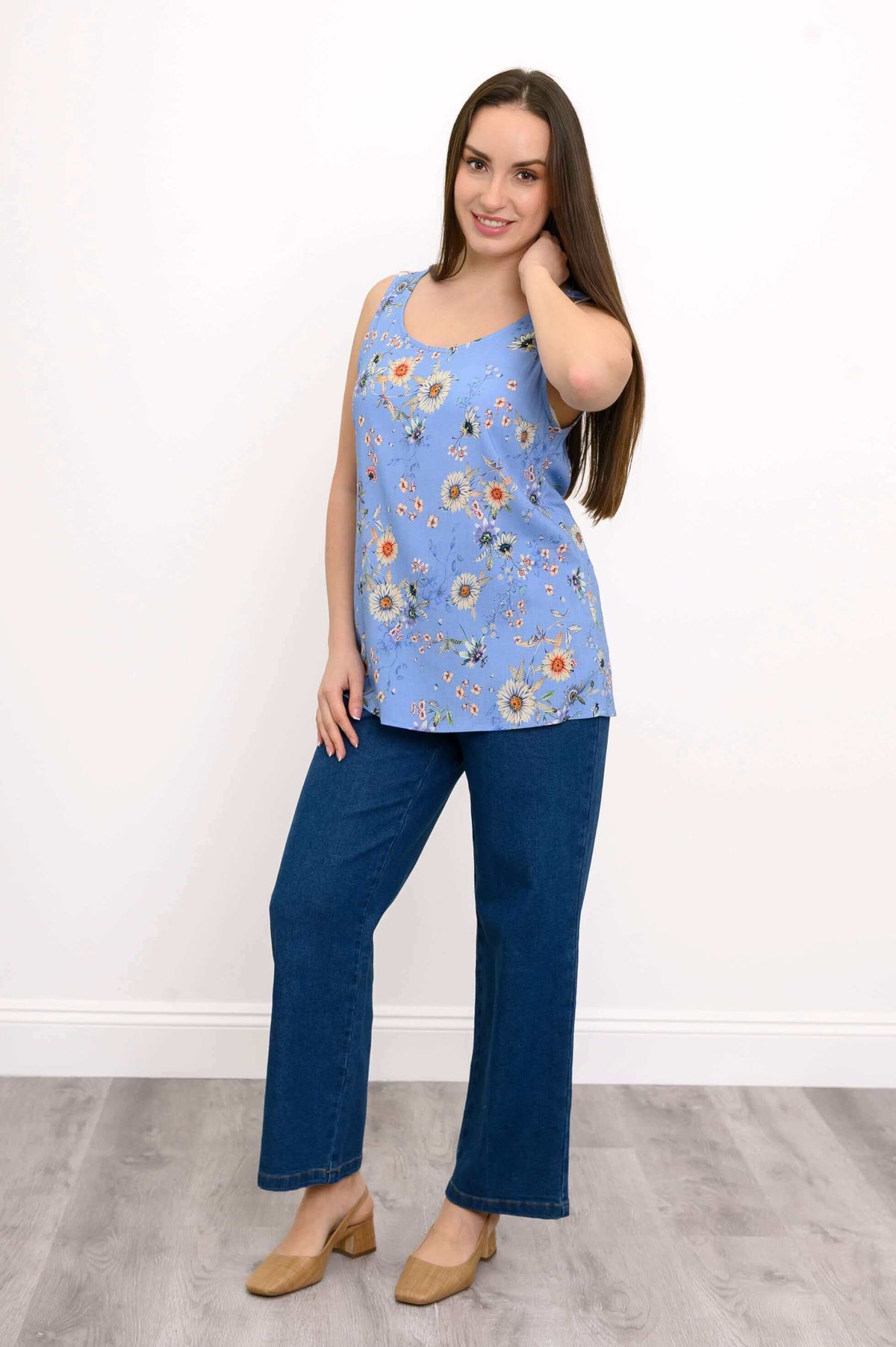 Woman posing in a blue floral tank top paired with blue jeans