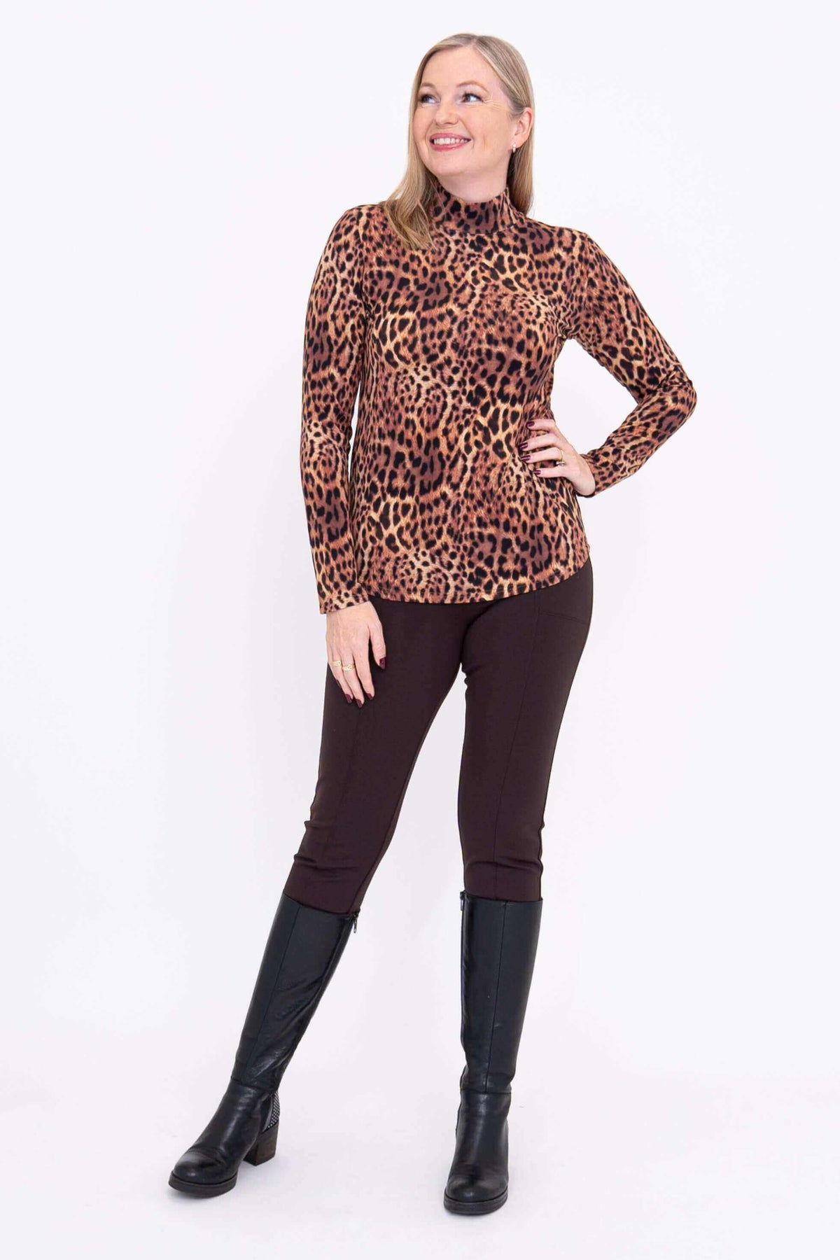 Woman posing in leopard print long sleeve mock neck top with hand on hip