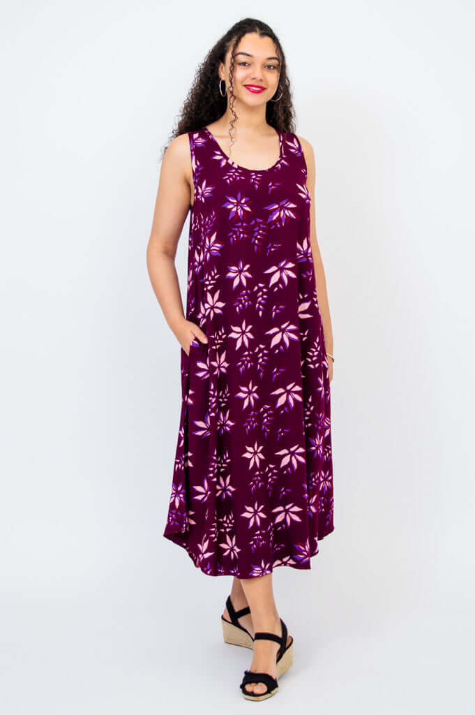 Woman wearing a sleeveless purple floral swing midi dress with pockets