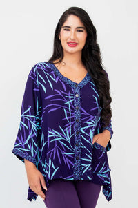 Woman wearing a purple bamboo print V-neck tunic top with button front and pockets