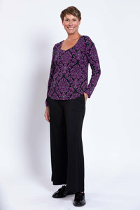Full body front view of model in purple patterned top and black wide-leg pants