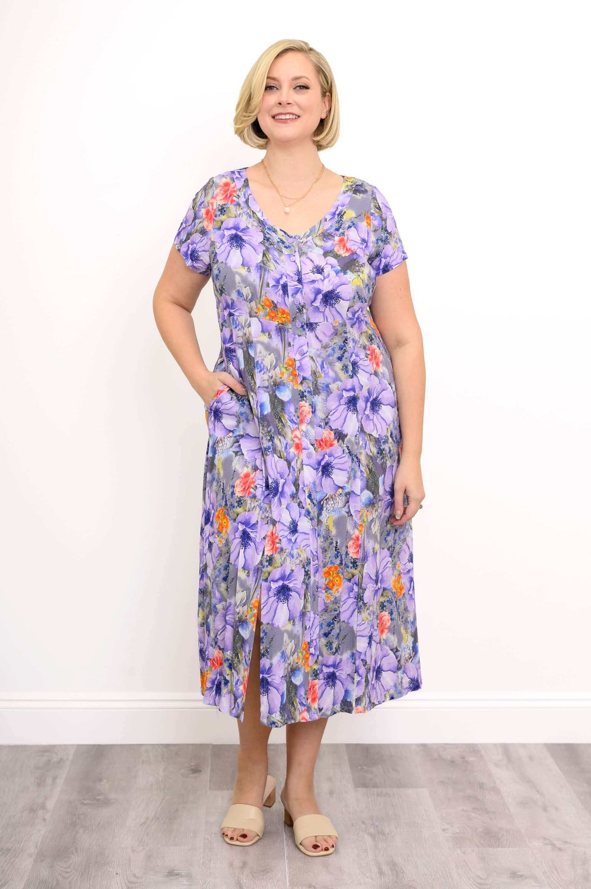 Full body front view of woman wearing purple floral maxi dress with her hand in her pocket