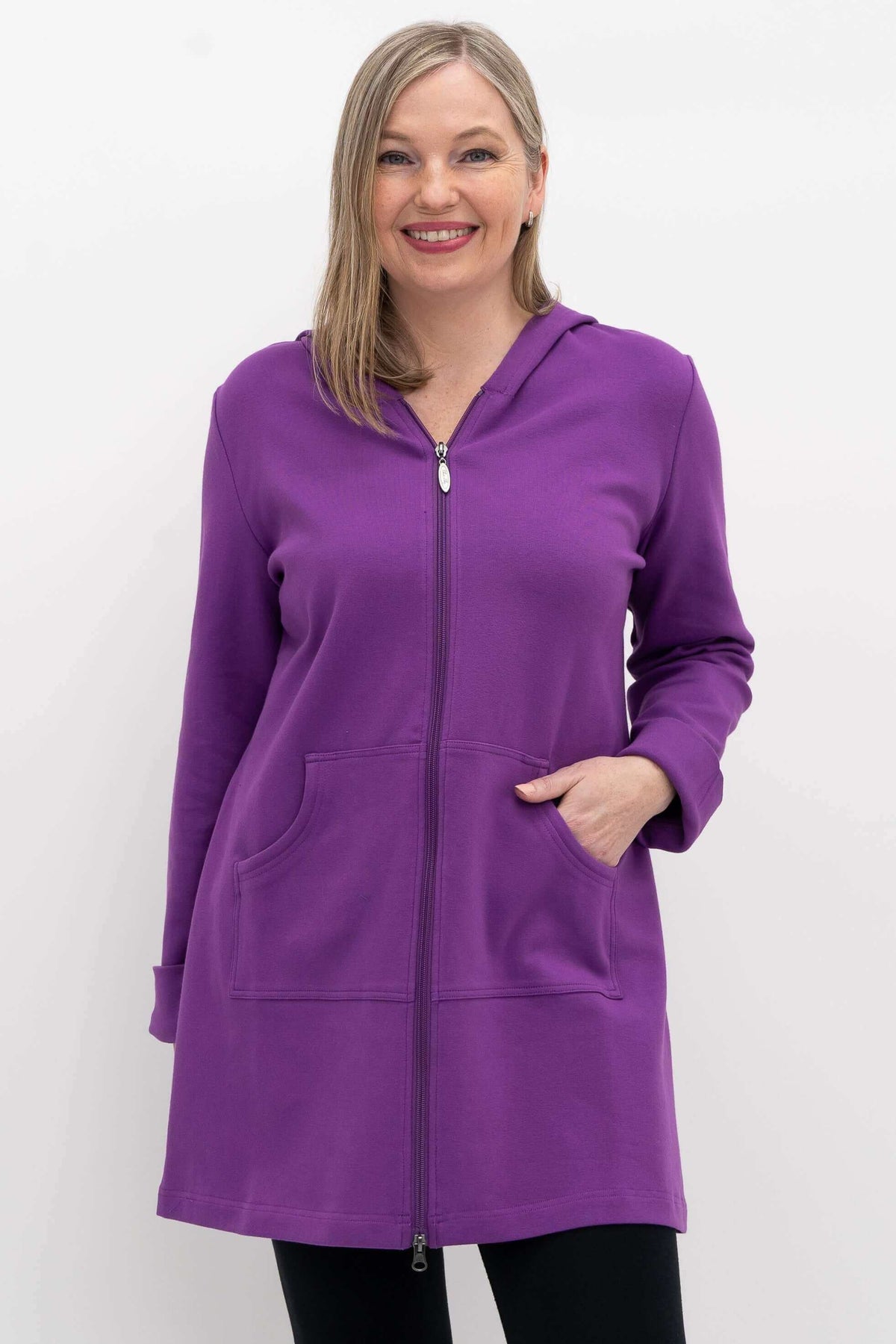 Woman wearing a vibrant purple hooded jacket with front pockets, smiling