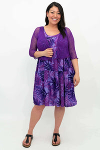 Woman in purple palm print dress with matching purple cardigan