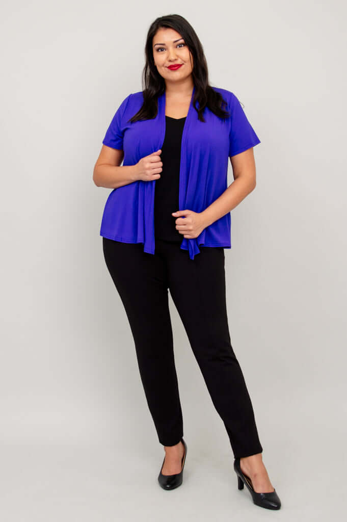 Model in a purple open-front short sleeve jacket and black pants, hand holding jacket edge