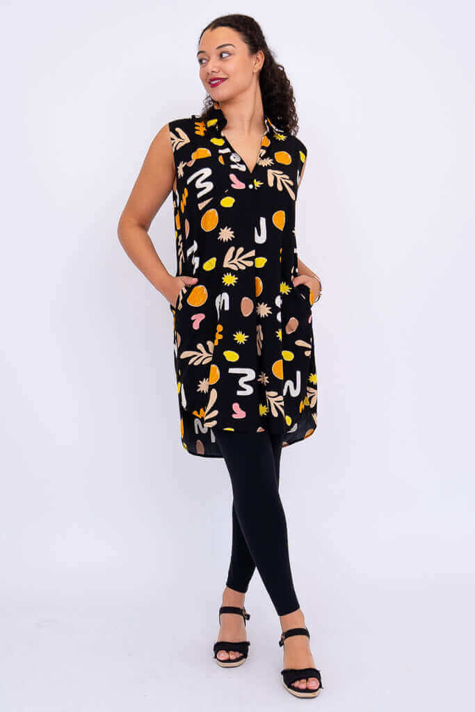 Side angle of Queenie sleeveless tunic with model smiling and hands in pockets