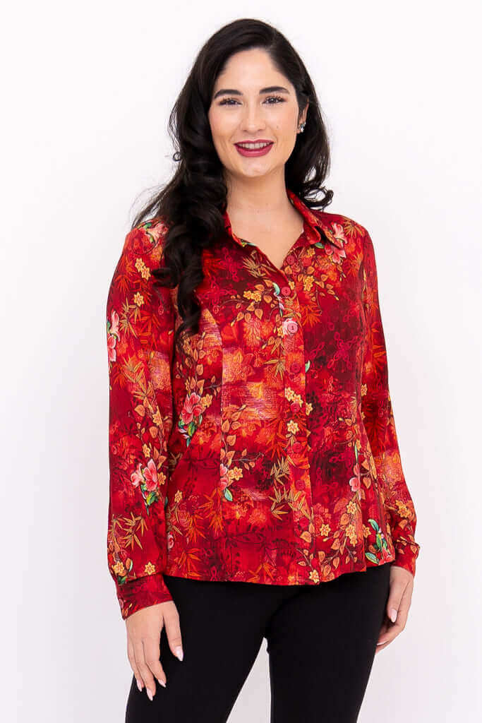 Woman wearing a vibrant red floral blouse with long sleeves and a classic collar