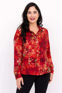 Woman wearing a vibrant red floral blouse with long sleeves and a classic collar