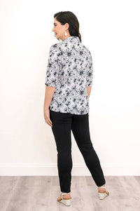 Rear angle view of woman wearing a white floral blouse with black floral pattern