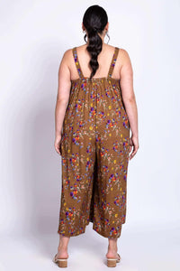 Person showing the back of a brown floral jumpsuit with wide legs and elastic straps