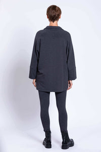 Rear view of a woman wearing a dark grey dolman sleeve jacket and leggings