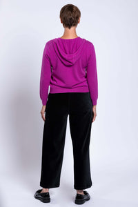 Back view of a woman wearing a magenta wool cashmere zip hoodie showing attached hood and relaxed fit.