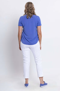 Rear view of woman wearing blue Tessa Tee with white pants and blue sneakers