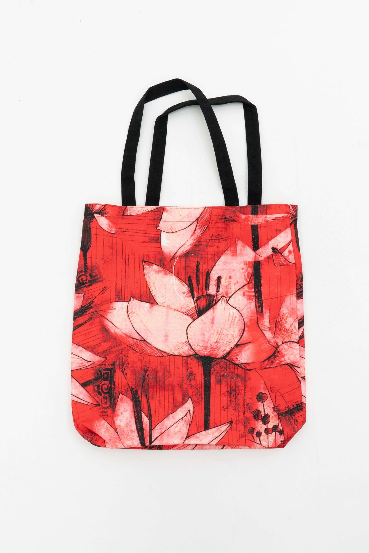 Red canvas tote bag with large artistic lotus flower print and black handles