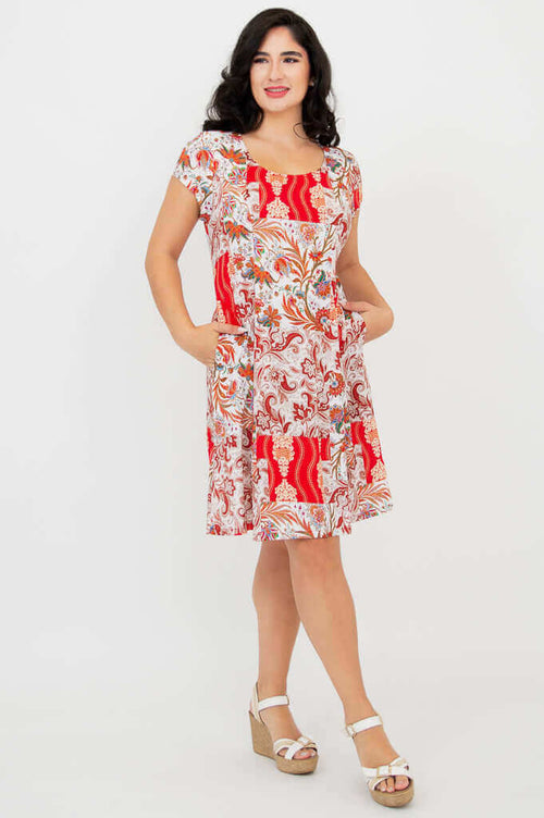 Woman wearing a red and white paisley print dress with pockets and wedge sandals